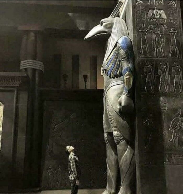 Person looking up at a giant ancient Egyptian statue, an image that can trigger fear in those with megalophobia.