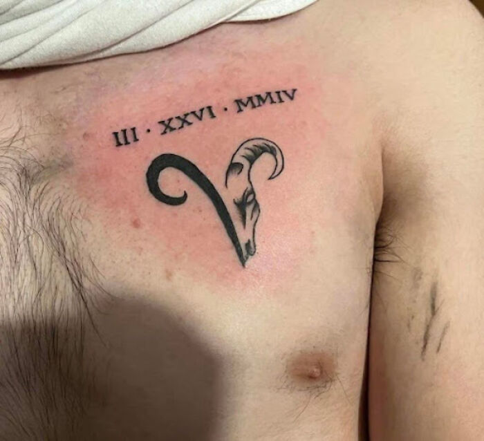 Aries tattoo on chest with Roman numerals, featuring a ram's head design. Aries tattoo on chest with Roman numerals, featuring a ram's head design.