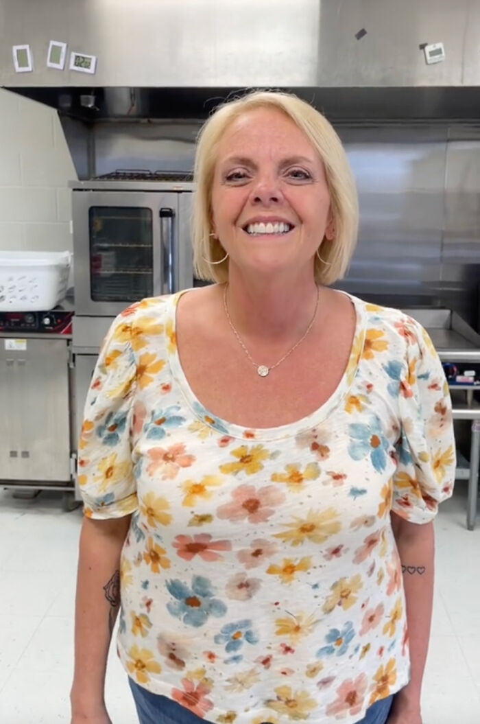 Smiling teacher in a floral shirt, standing in a classroom setting. Smiling teacher in a floral shirt, standing in a classroom setting.