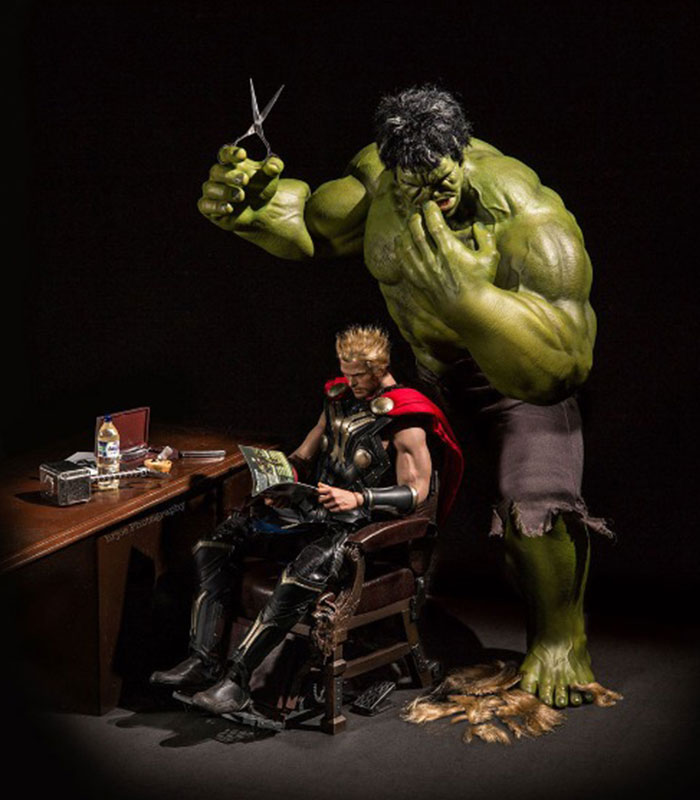 An action figure scene featuring Hulk standing behind Thor, who is sitting in a chair reading a magazine. Hulk is holding a pair of scissors above Thor’s head, looking focused as if about to give him a haircut. Thor appears relaxed and unaware of Hulk’s actions. An action figure scene featuring Hulk standing behind Thor, who is sitting in a chair reading a magazine. Hulk is holding a pair of scissors above Thor’s head, looking focused as if about to give him a haircut. Thor appears relaxed and unaware of Hulk’s actions.