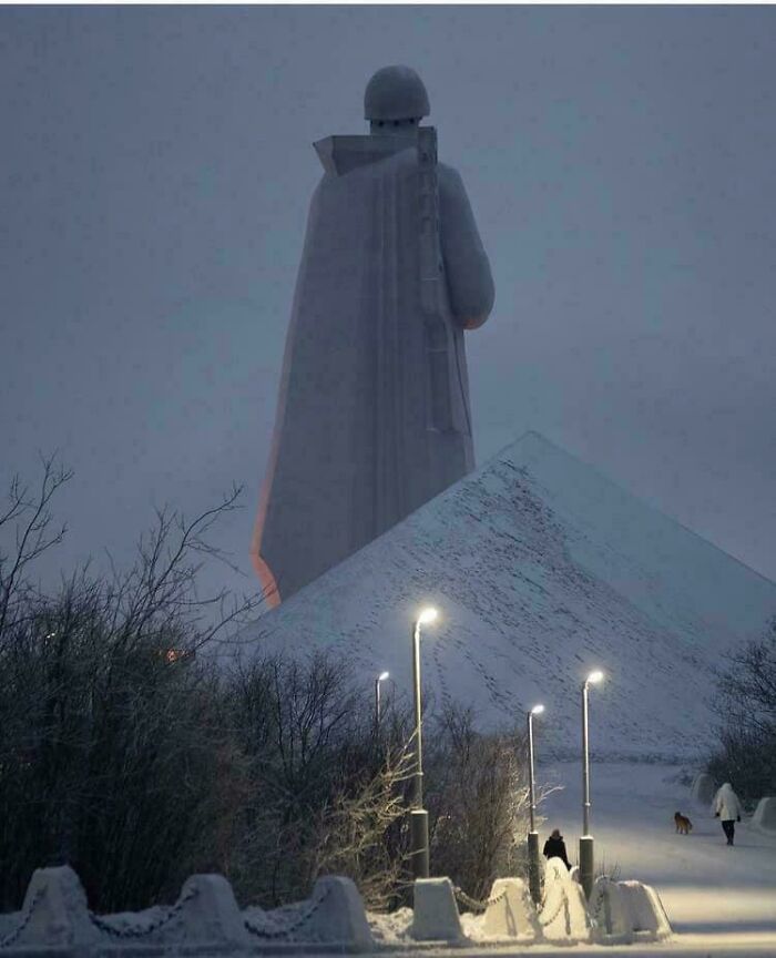 Massive statue towering over snowy landscape at dusk, evoking fear for anyone with megalophobia.