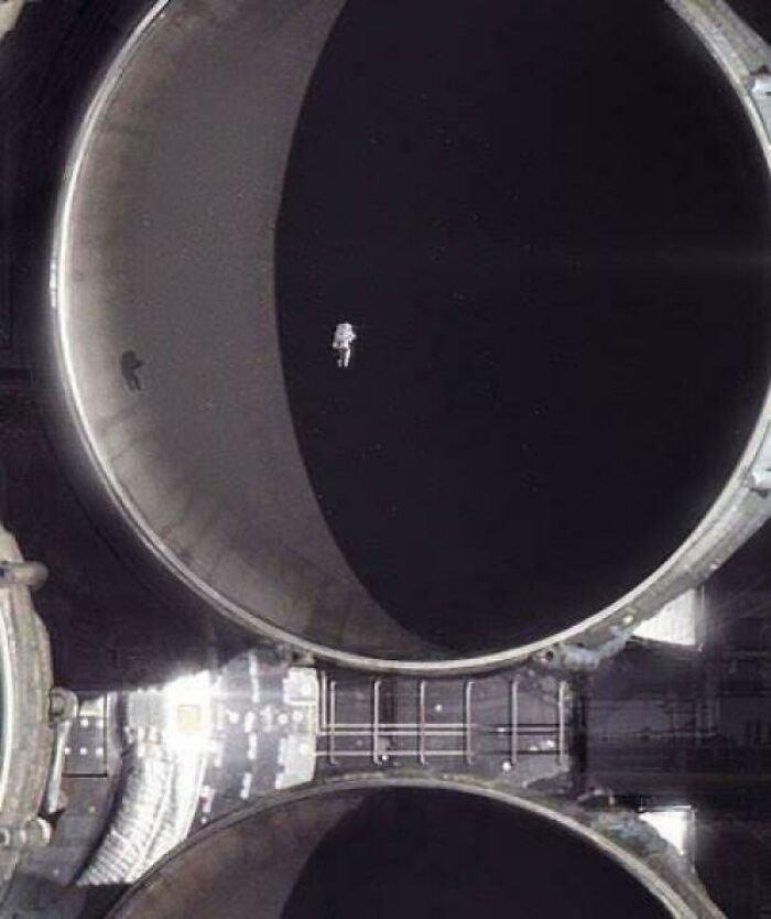 Astronaut floating in front of a massive dark circular structure, evoking megalophobia with its overwhelming size and scale.
