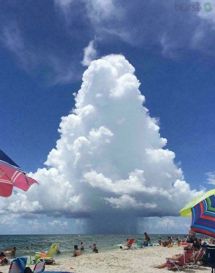 Massive towering cloud formation over beachgoers creating a striking image for megalophobia fear.