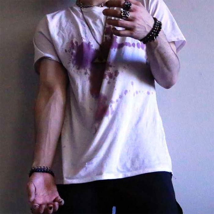 A photo of a person wearing a stained white T-shirt, showing their arms and hands, accessorized with bracelets and rings. A photo of a person wearing a stained white T-shirt, showing their arms and hands, accessorized with bracelets and rings.