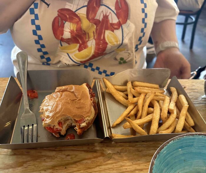 Burger and fries served in a divided metal tray, showcasing one of the most ridiculous food serving styles in restaurants.