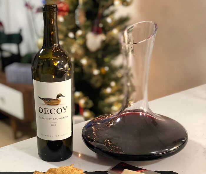 Bottle of red wine and wine decanter on table, adding small luxuries for hosting Thanksgiving with an elegant touch.