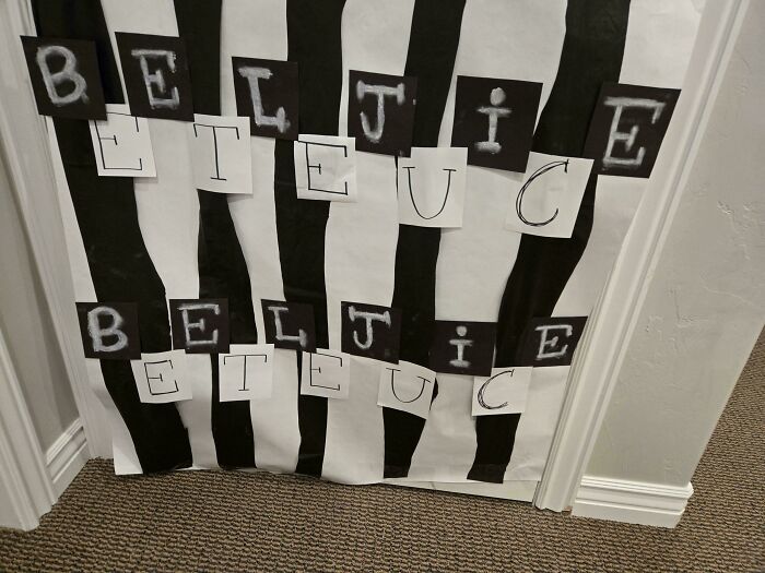 Sign fail showing jumbled letters on a black and white striped background.