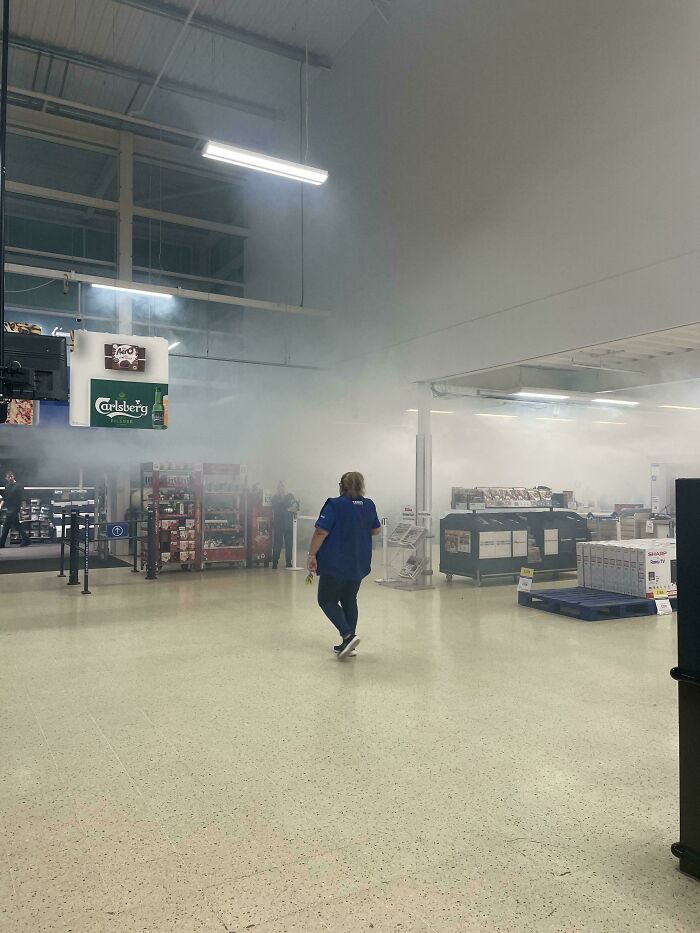 Supermarket scene with a person walking amidst a smoky haze, displaying British humor in everyday life.