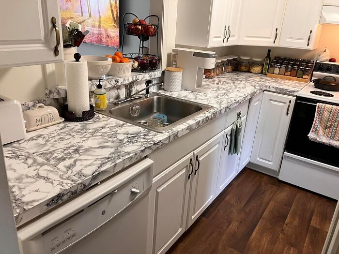 Marble-patterned kitchen countertop makeover, showcasing genius hacks to conceal eyesores and refresh the space with style.