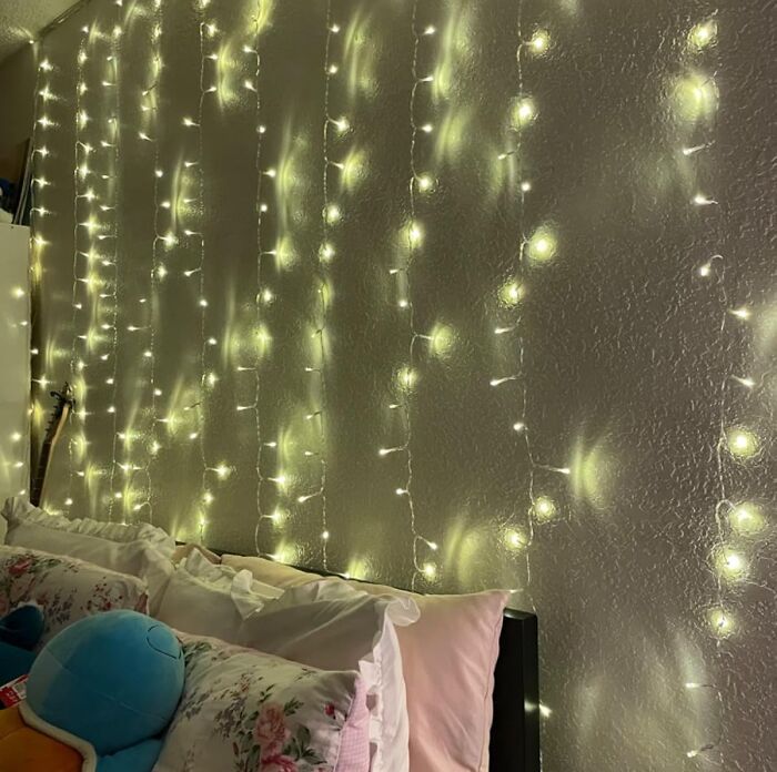 Cozy bedroom corner with string lights on wall, using genius hacks to conceal pesky eyesores and brighten the space.