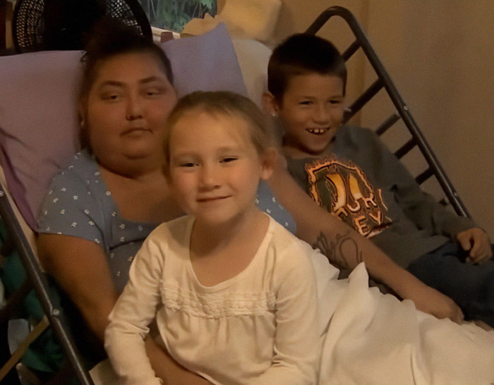 Single mom in hospital bed with two children, evoking community support after terminal diagnosis. Single mom in hospital bed with two children, evoking community support after terminal diagnosis.