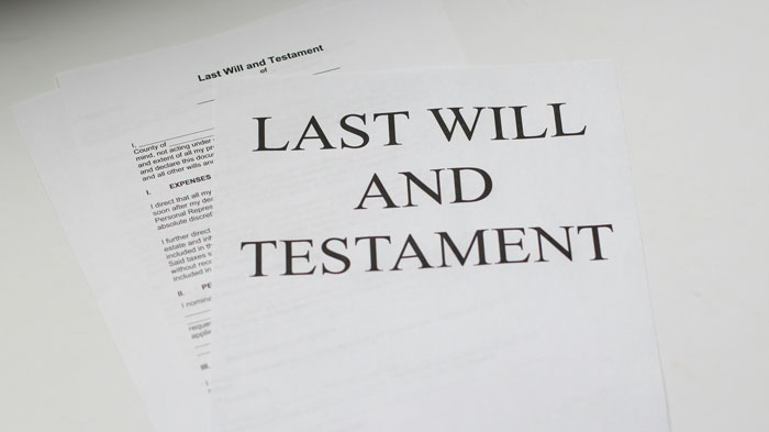 Close-up of a "Last Will and Testament" document on a white surface, related to inheritance sharing. Close-up of a "Last Will and Testament" document on a white surface, related to inheritance sharing.