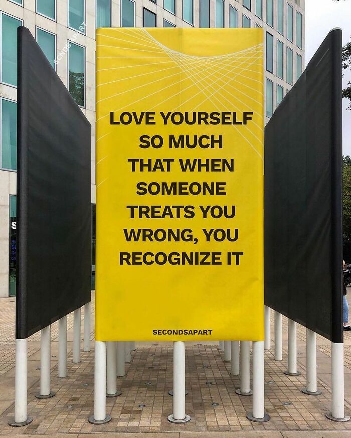 Yellow street message board in London with a wholesome quote about self-love, part of wholesome messages uplifting people’s hearts.