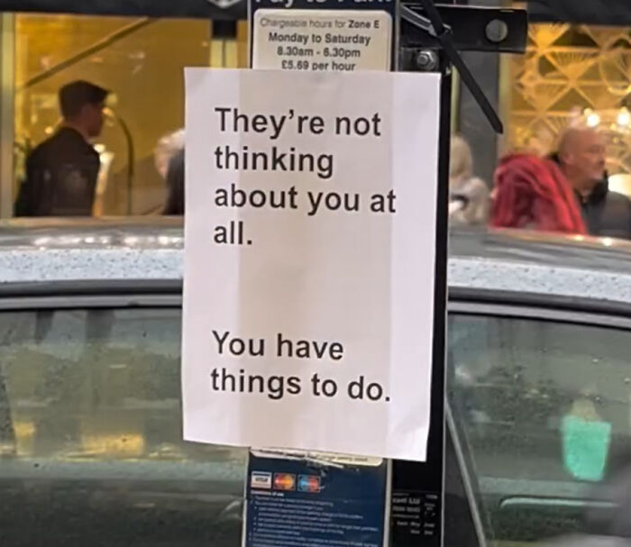 Wholesome message on a street sign in London reminding people to focus on their own tasks and not worry about others.