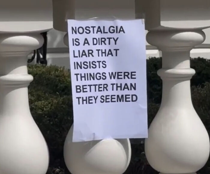 Sign on a white balustrade in London streets with a wholesome message about nostalgia and perception of the past.
