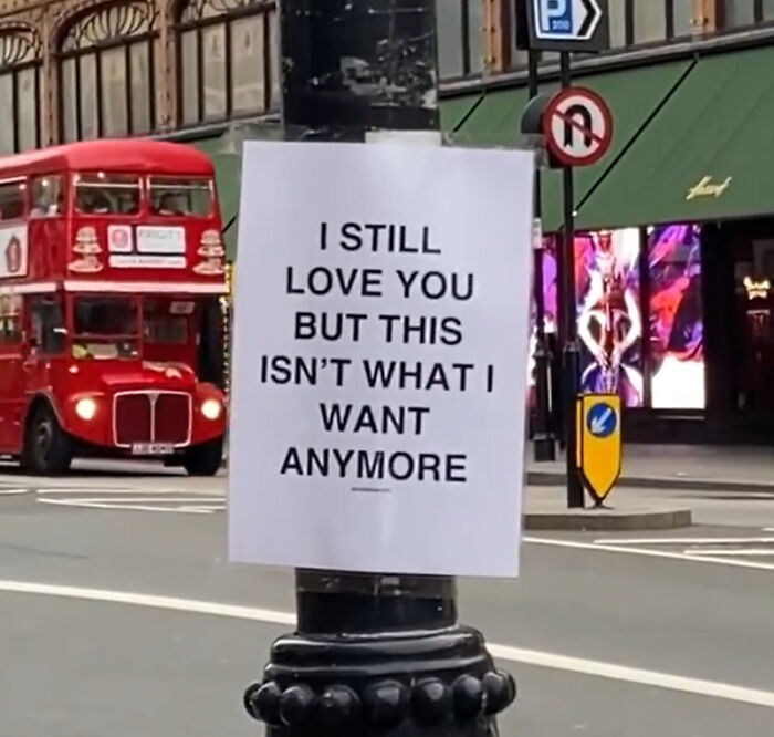 Wholesome message on a London street pole with a classic red double-decker bus and urban backdrop visible.