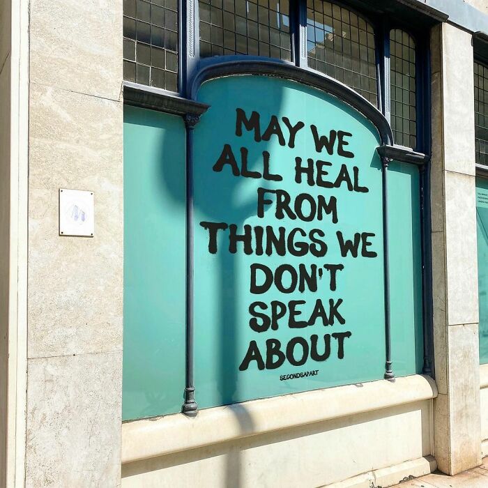 Wholesome message painted on a London street wall, encouraging healing from unspoken pain in urban surroundings.