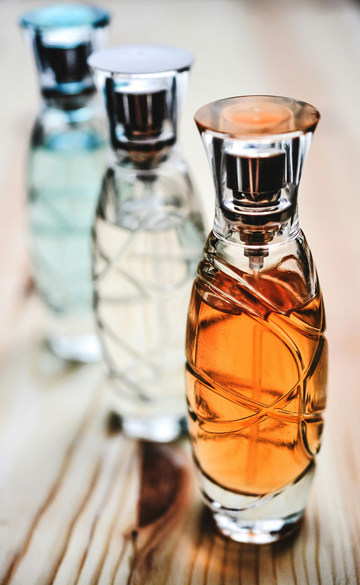 Three elegant perfume bottles in a row, each containing different colored liquids, representing a collection of high-end fragrances. Three elegant perfume bottles in a row, each containing different colored liquids, representing a collection of high-end fragrances.