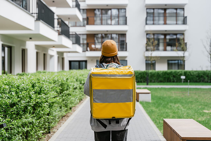Delivery person in yellow uniform walking through a residential area. Delivery person in yellow uniform walking through a residential area.