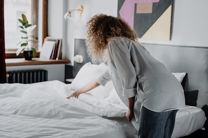 Woman inspecting an unmade bed, expressing dissatisfaction at boyfriend's room condition. Woman inspecting an unmade bed, expressing dissatisfaction at boyfriend's room condition.