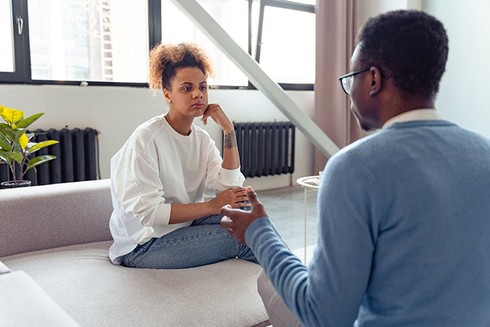 Woman looking serious while talking to her boyfriend in a bright living room setting. Woman looking serious while talking to her boyfriend in a bright living room setting.