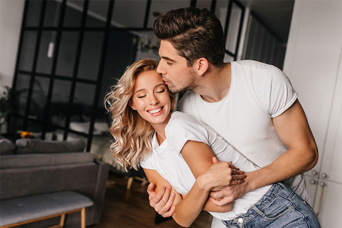 Couple embracing happily in a modern living room, symbolizing family tradition versus friendship priorities. Couple embracing happily in a modern living room, symbolizing family tradition versus friendship priorities.