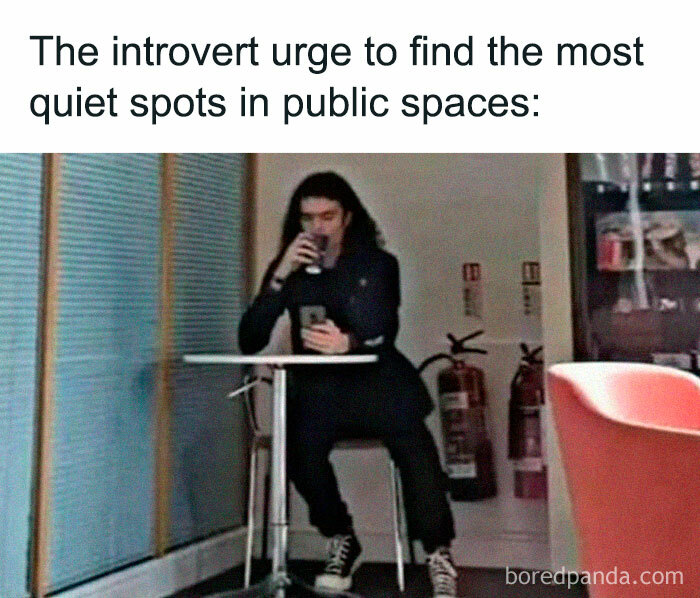 A person sitting alone in a quiet corner of a public space, sipping a drink and using a phone, symbolizing solitude.