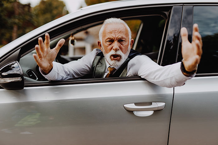 Elderly man angrily gesturing from car window, highlighting sexism issue. Elderly man angrily gesturing from car window, highlighting sexism issue.