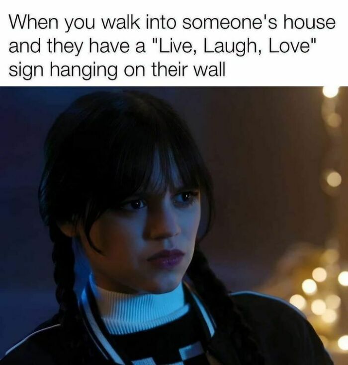 Person looks unimpressed with "Live, Laugh, Love" sign, relatable to those done interacting with others.