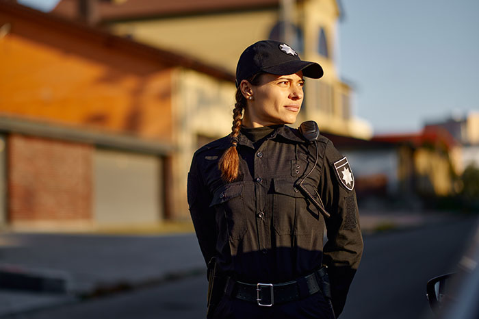 A confident female police officer stands in uniform outdoors, representing resilience against sexism. A confident female police officer stands in uniform outdoors, representing resilience against sexism.