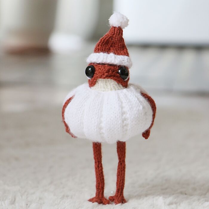 Knitted miniature frog wearing a Santa hat, created by a French artist.