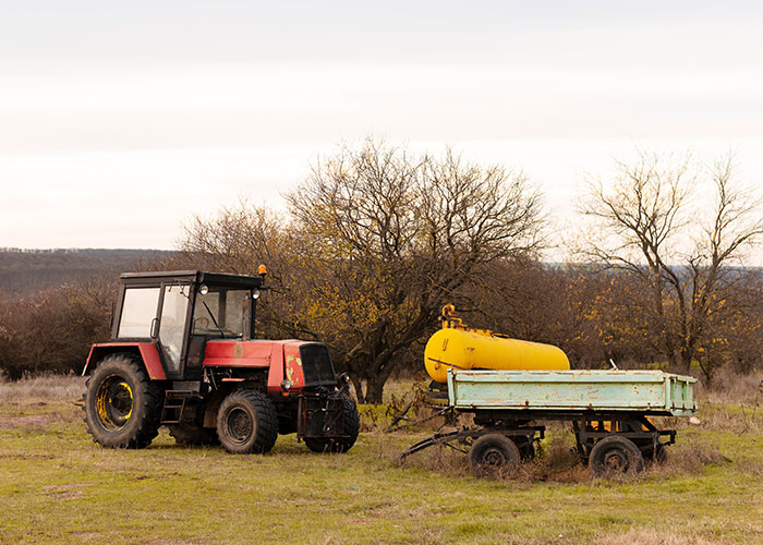 Tractor on a field with bare trees and equipment, symbolizing a farmer's defiance to HOA demands. Tractor on a field with bare trees and equipment, symbolizing a farmer's defiance to HOA demands.