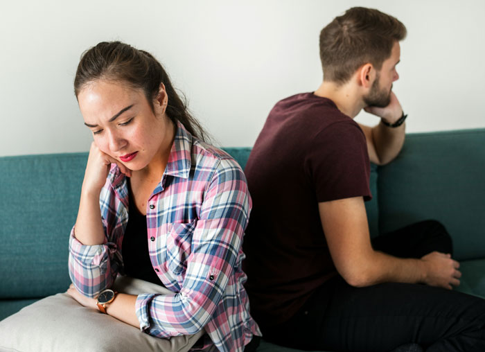 Father supports son; family drama unfolds on a couch, woman upset, man indifferent. Father supports son; family drama unfolds on a couch, woman upset, man indifferent.