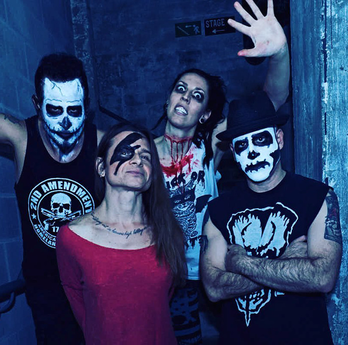 Rock singer with bandmates wearing face paint and dark clothing, posing in a dimly lit corridor. Rock singer with bandmates wearing face paint and dark clothing, posing in a dimly lit corridor.