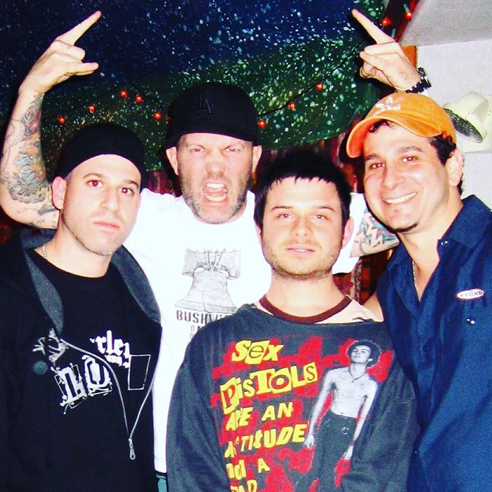 Rock singer with friends, wearing casual shirts and hats, posing energetically in a vibrant setting. Rock singer with friends, wearing casual shirts and hats, posing energetically in a vibrant setting.