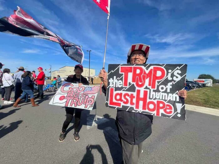 People holding signs with spelling errors at a political rally, illustrating sign fails.