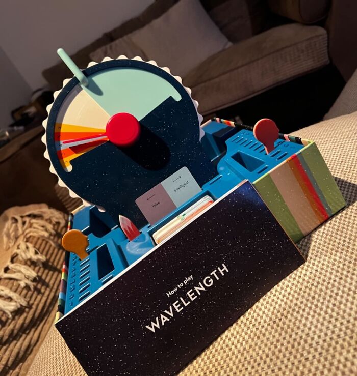 Compact and straightforward game Wavelength with colorful gameboard and cards set on a couch in a cozy living room.