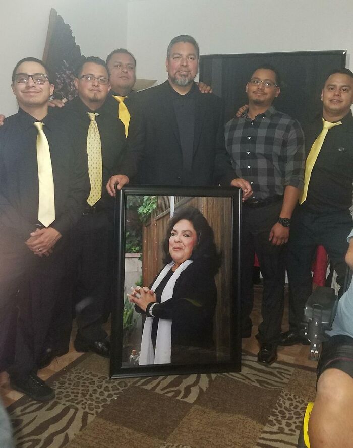 Group of men dressed formally, holding a large framed portrait, celebrating a wholesome adoption story.