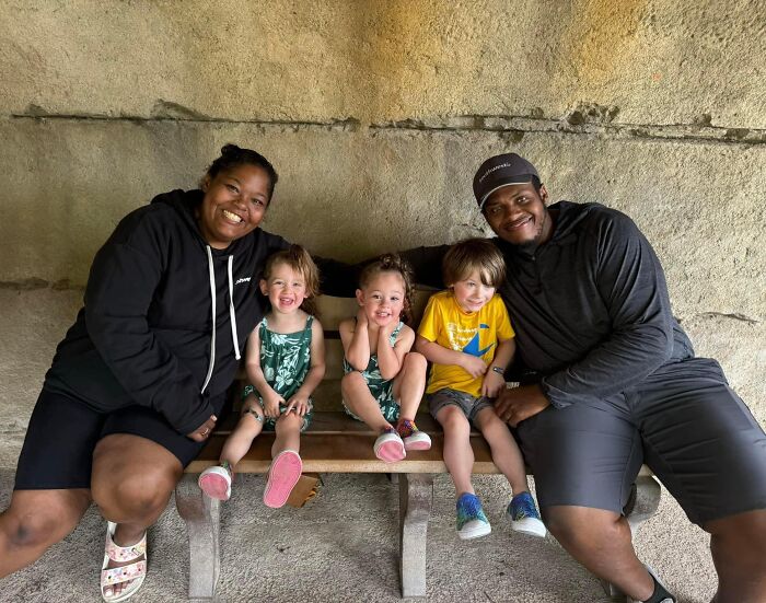 Happy family with three children sitting on a bench, embodying a wholesome adoption story.