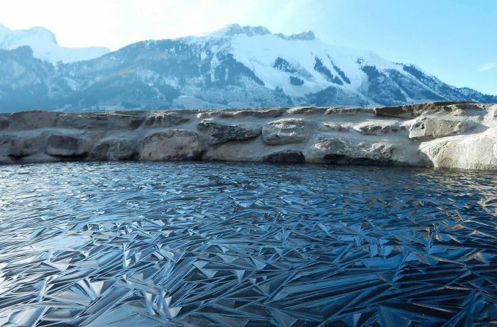 Ice-cold winter scene with a frozen lake and snow-covered mountains in the background.
