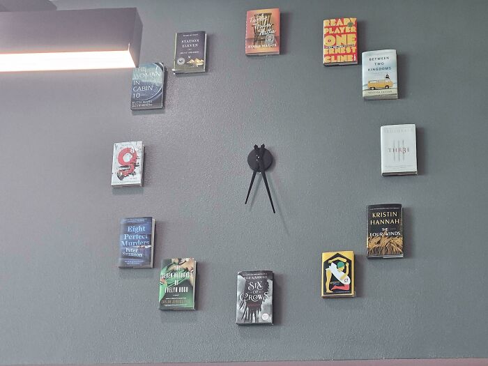 Creative clock design using books as hour markers on a wall.
