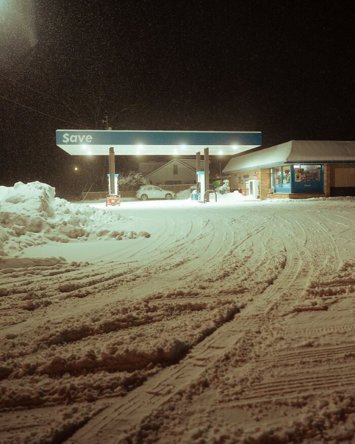 Snow-covered gas station at night, showcasing ice-cold winter scenery with snow-covered ground and buildings.