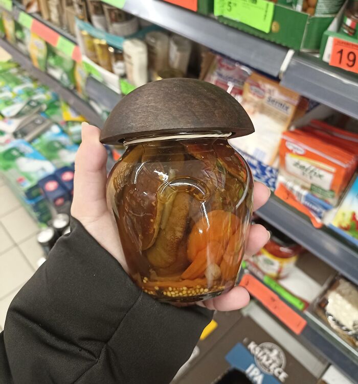 Innovative design of a jar shaped like a mushroom held in a hand, seen in a grocery store aisle.