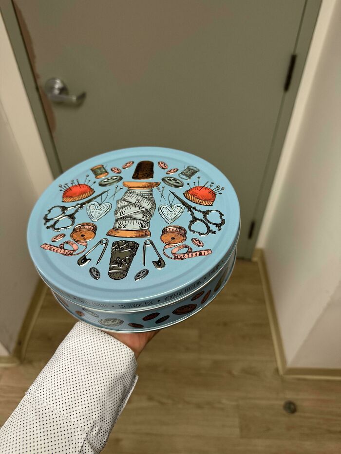 Creative design on a sewing box tin, showcasing detailed illustrations of sewing tools.