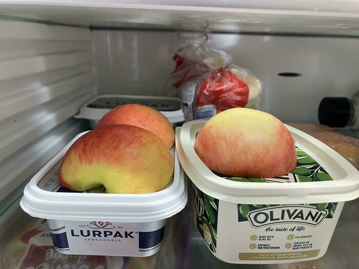 Apples in butter containers inside a fridge, showcasing infuriating family members' habits.
