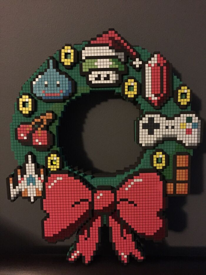 Pixel art Christmas wreath with gaming icons and a red bow, perfect for amazing mothers-in-law who love video games.