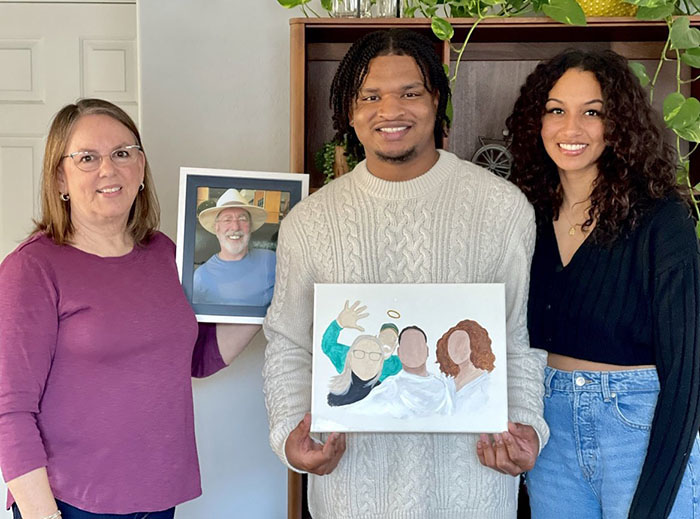 Three people celebrating viral Thanksgiving tradition, holding a portrait and painting. Three people celebrating viral Thanksgiving tradition, holding a portrait and painting.