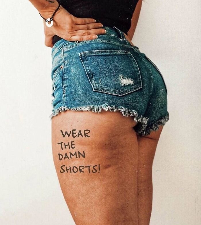 Woman wearing denim shorts with a message "Wear the d**n shorts!" written on her thigh.