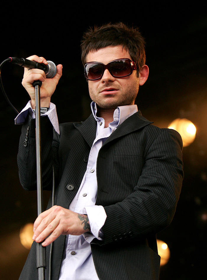 Rock singer performing on stage, wearing sunglasses and a pinstripe suit, holding a microphone. Rock singer performing on stage, wearing sunglasses and a pinstripe suit, holding a microphone.