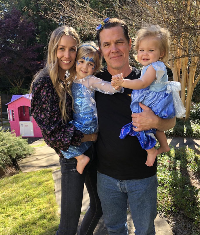 Happy family outdoors, featuring Josh Brolin holding two children and standing with a woman in a garden setting. Happy family outdoors, featuring Josh Brolin holding two children and standing with a woman in a garden setting.
